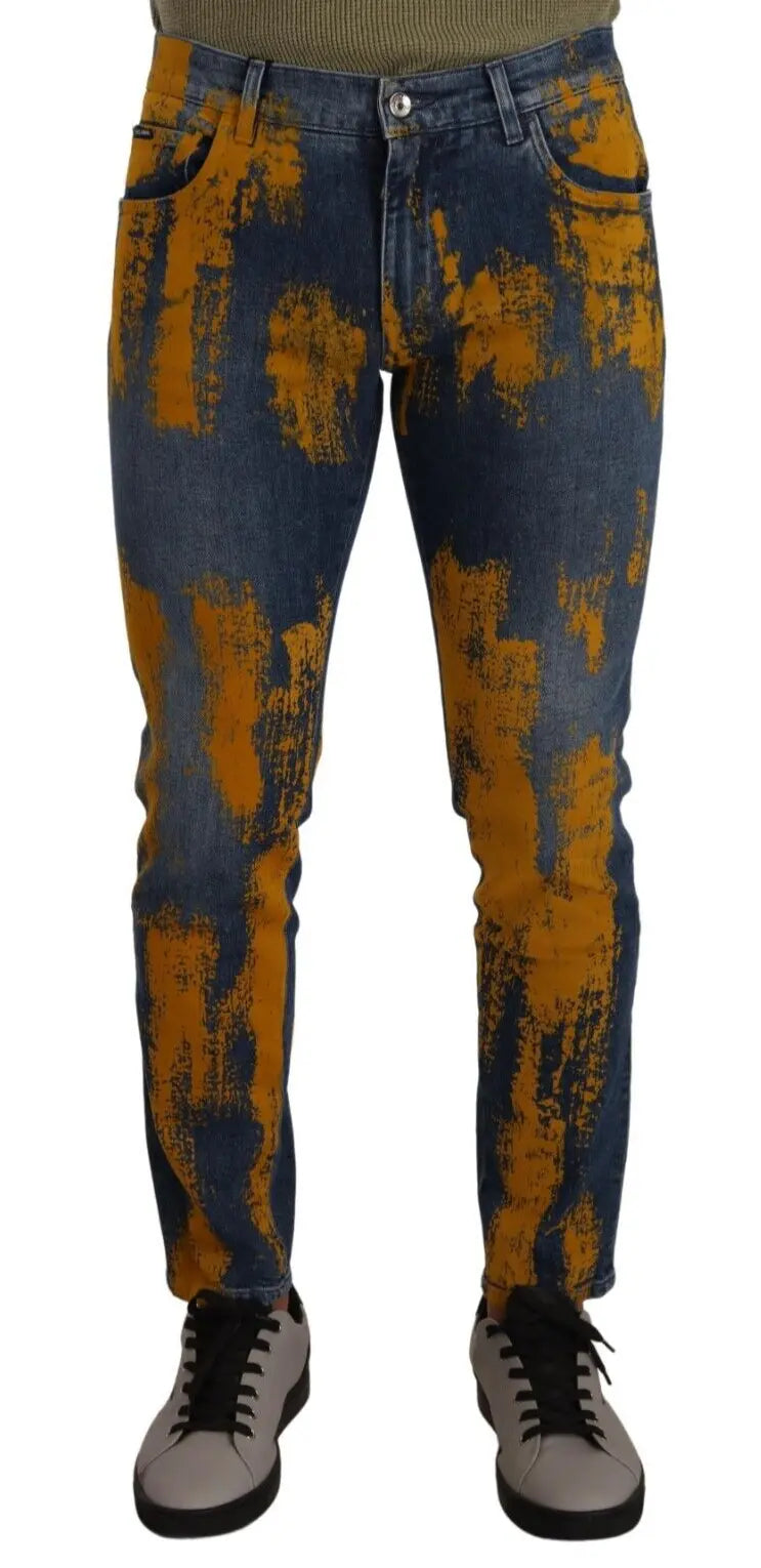 Men’s skinny denim jeans in blue with bold yellow dye splatter, button and zip front closure.