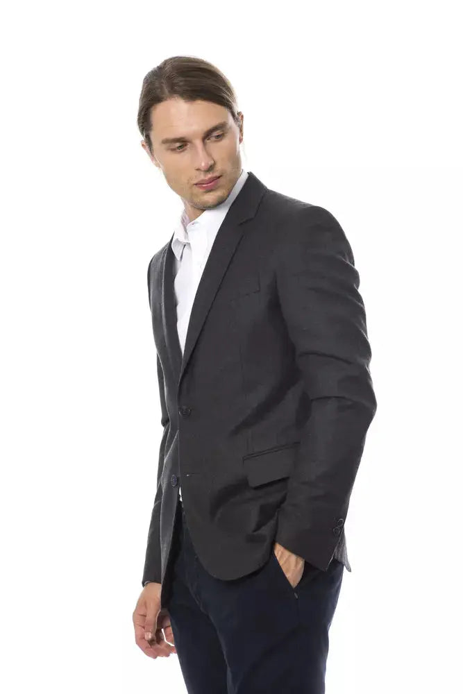 Men's dark gray wool blazer with notch lapels and two-button closure, worn over white dress shirt.