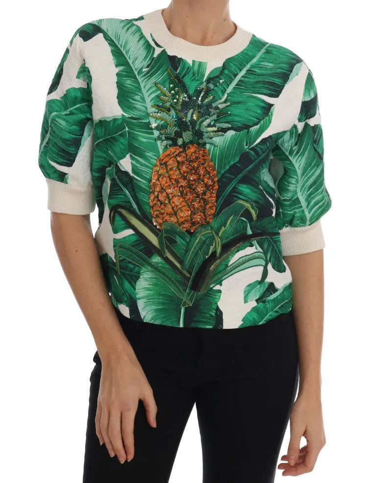 White crewneck sweater with green tropical leaves and a large sequin pineapple embellishment on front.