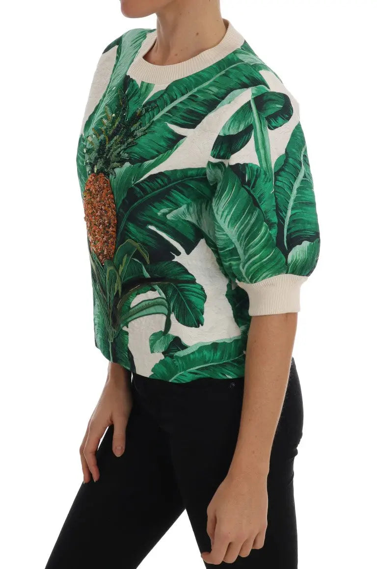 White crewneck sweater with green tropical leaves and a large sequin pineapple embellishment on front.