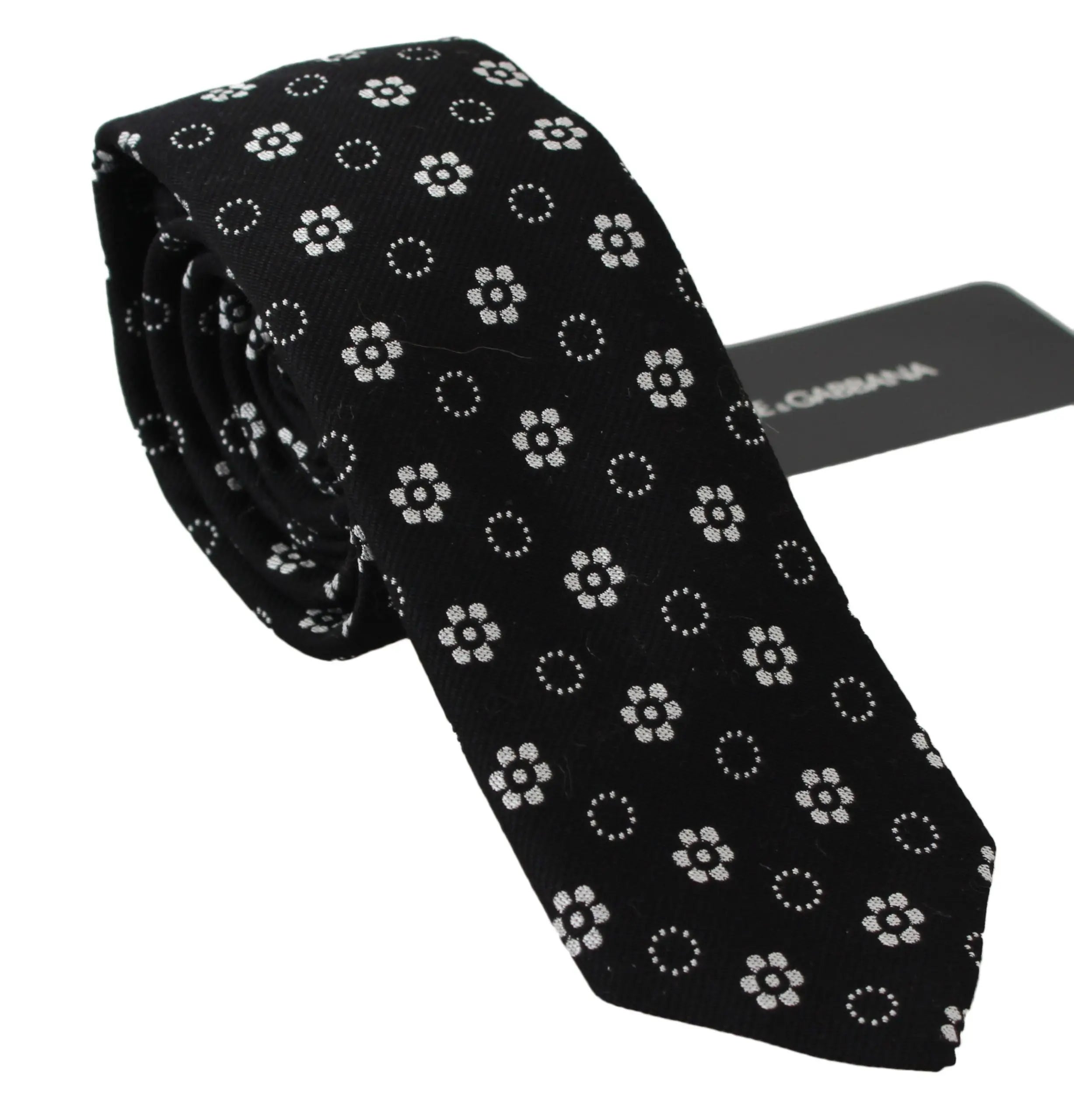 Black silk tie with white floral and dotted pattern, classic narrow shape.