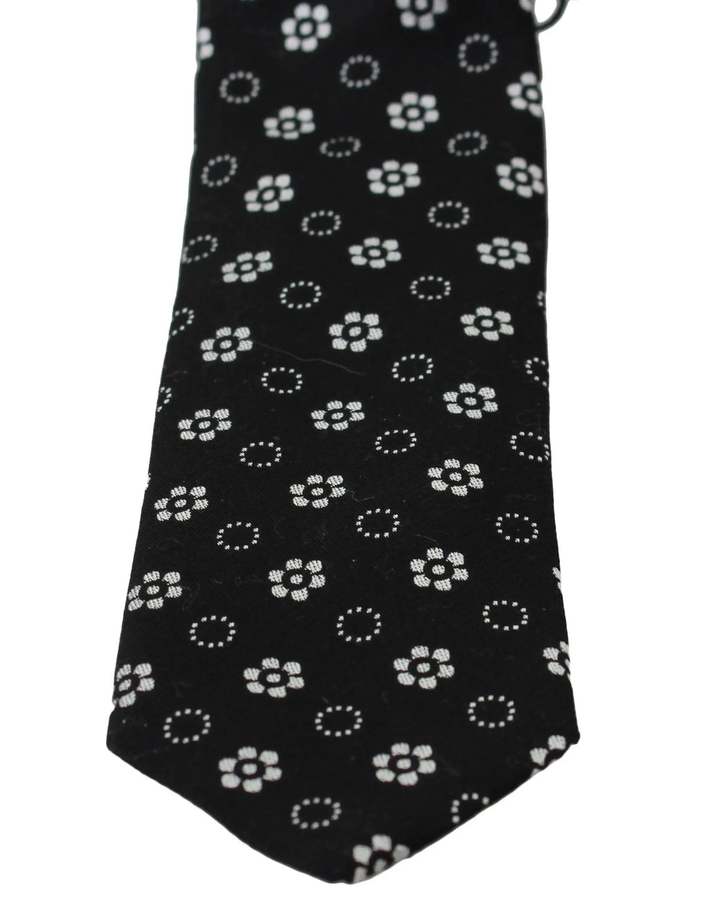 Black silk tie with white floral and dotted pattern, classic narrow shape.