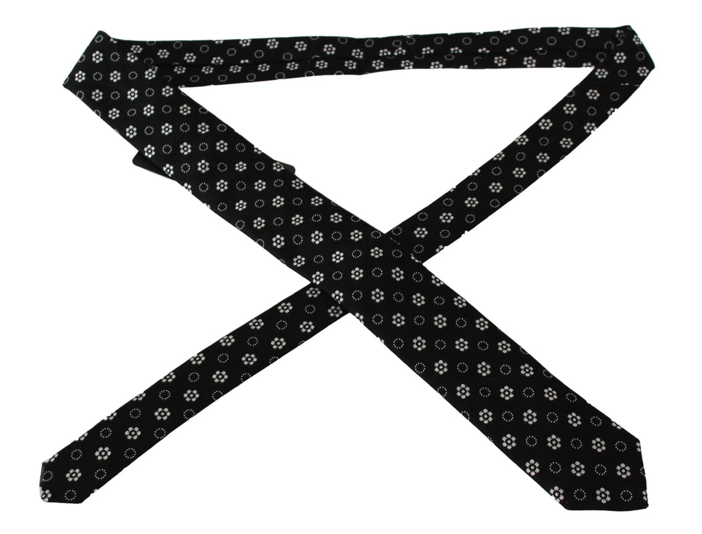 Black silk tie with white floral and dotted pattern, classic narrow shape.