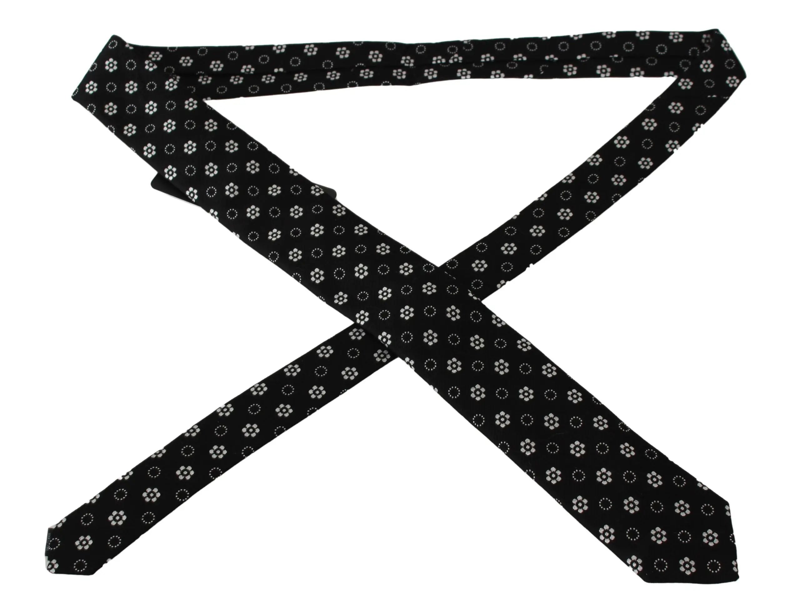 Black silk tie with white floral and dotted pattern, classic narrow shape.