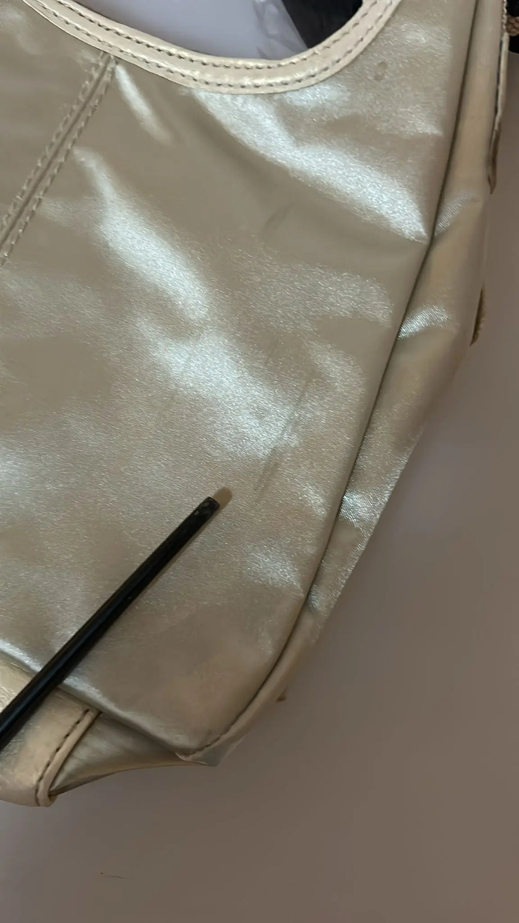 White fabric crossbody sling bag with beige trim and adjustable striped shoulder strap.