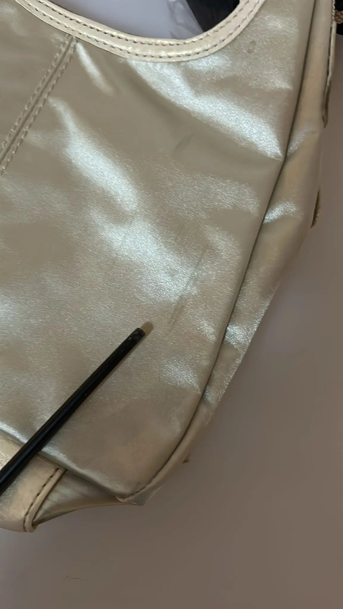 White fabric crossbody sling bag with beige trim and adjustable striped shoulder strap.